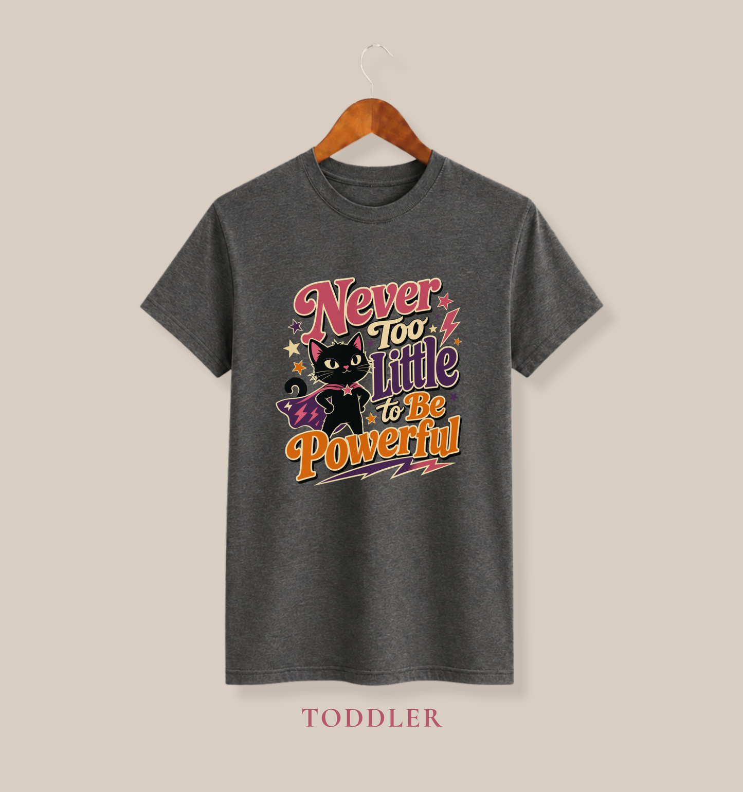 Asphalt grey toddler T-shirt featuring a superhero black cat in a purple cape surrounded by colorful stars and the empowering phrase “Never Too Little to Be Powerful.”