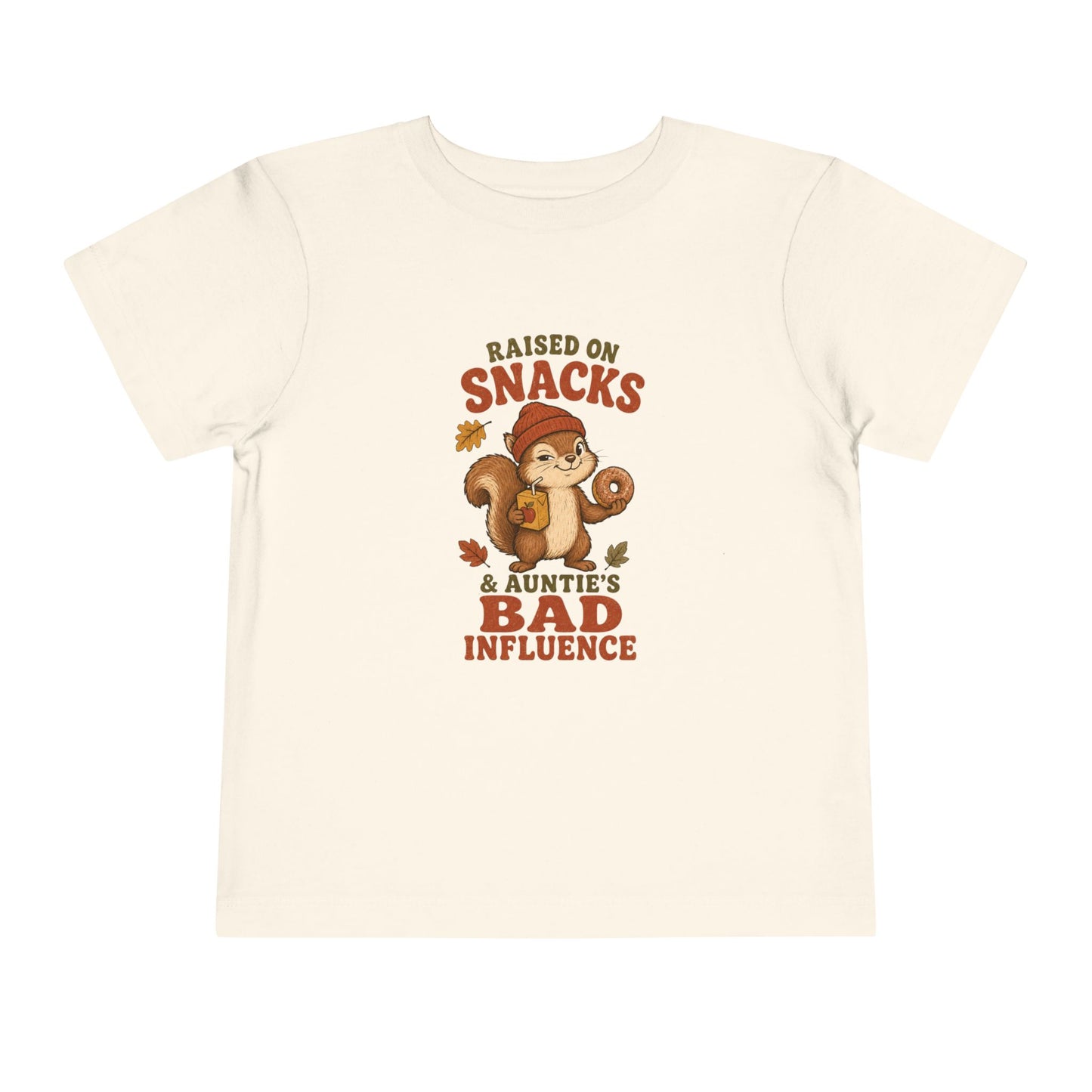 Natural color toddler T-shirt featuring a squirrel holding a donut and juice box, autumn leaves, and the phrase “Raised on Snacks & Auntie’s Bad Influence.”