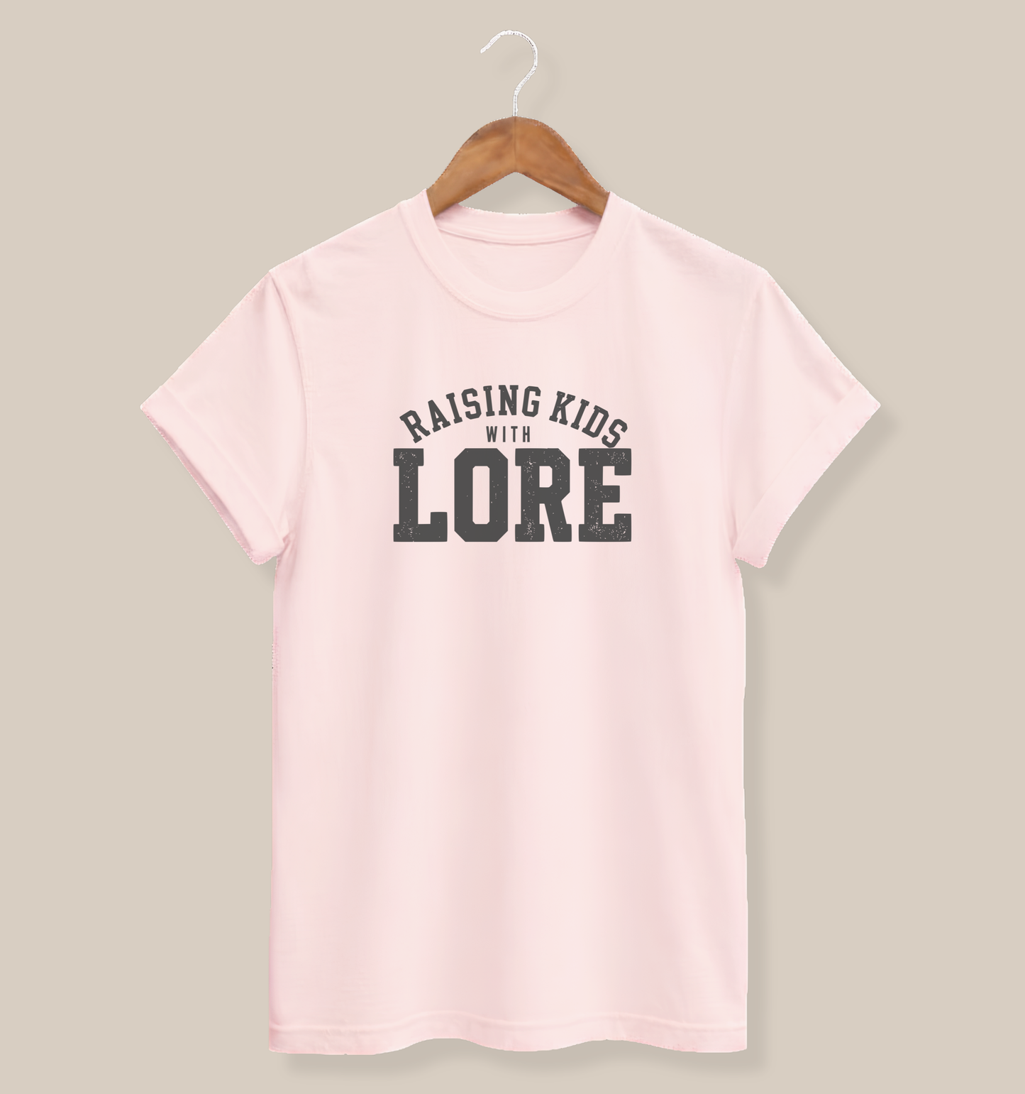Soft pink adult T-shirt featuring a lightly distressed charcoal design and the humorous saying “Raising Kids With Lore.”