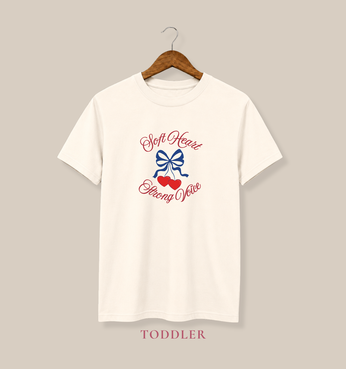 Natural toddler T-shirt featuring a navy bow, red hearts, and the empowering phrase “Soft Heart Strong Voice.”