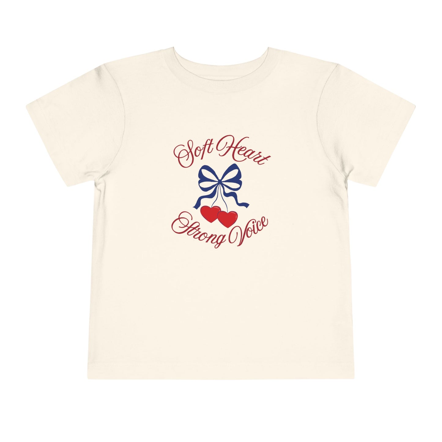 Natural color toddler T-shirt featuring a navy bow, red hearts, and the empowering phrase “Soft Heart Strong Voice.”