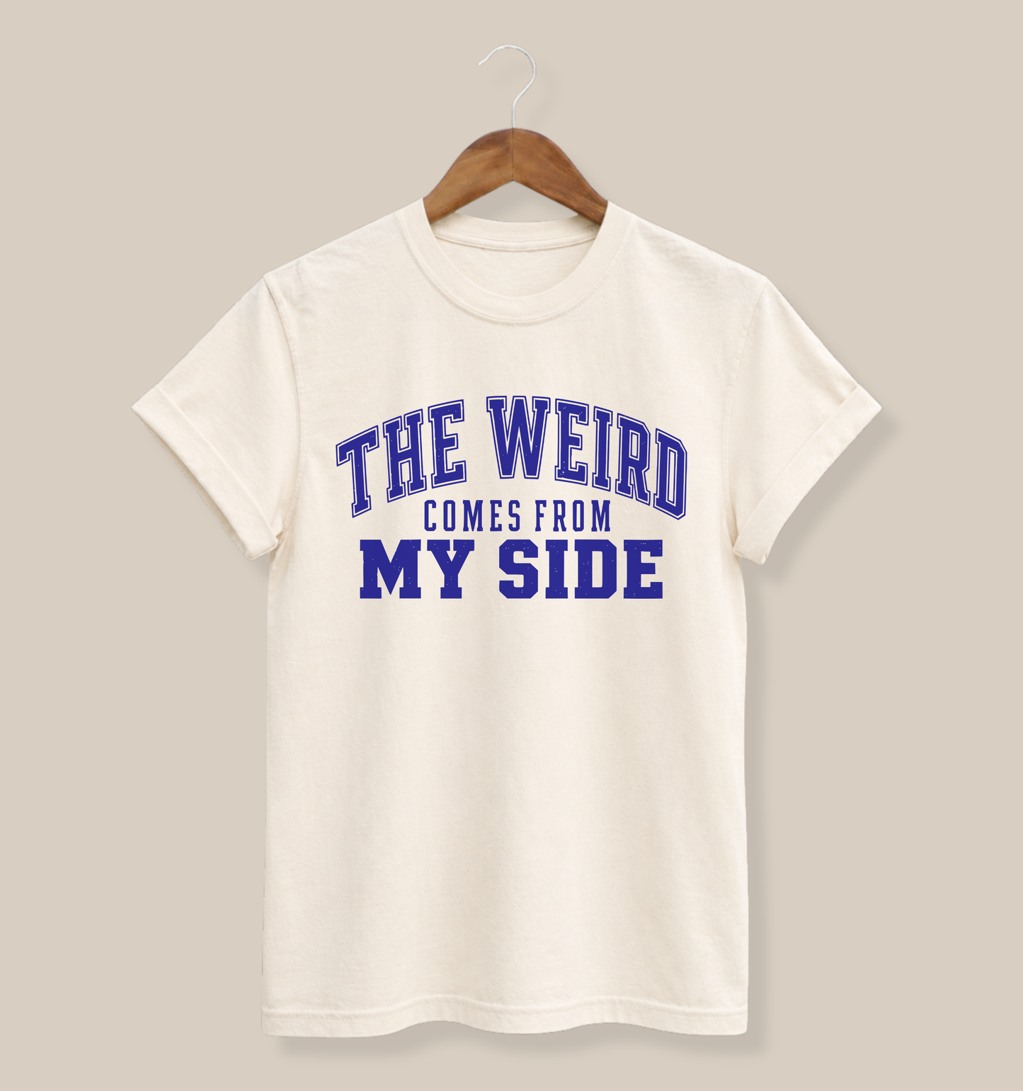 Ivory garment-dyed adult T-shirt featuring a distressed blue varsity design with the funny family phrase “The Weird Comes From My Side.”