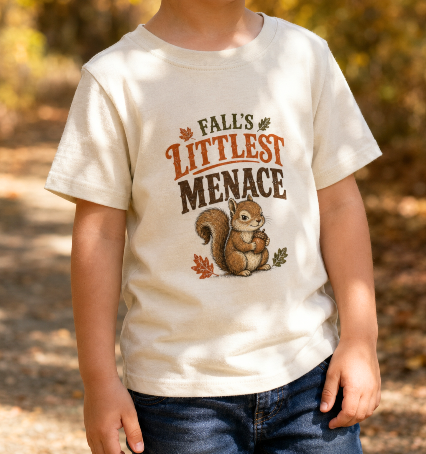 Natural toddler t-shirt featuring a cute squirrel holding an acorn with the phrase "Fall's Littlest Menace." Funny fall toddler graphic tee perfect for autumn adventures, pumpkin patches, Halloween, family photos, and everyday seasonal wear.