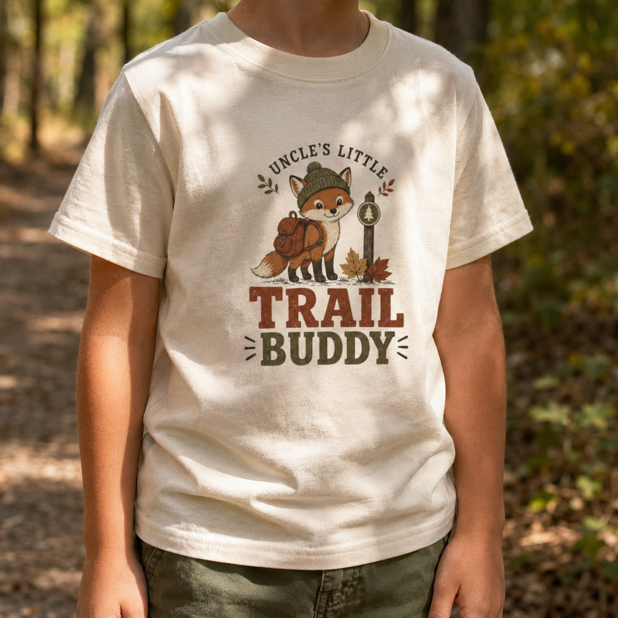 Child wearing a natural toddler T-shirt featuring a backpack-wearing fox, autumn leaves, and the phrase “Uncle’s Little Trail Buddy.”