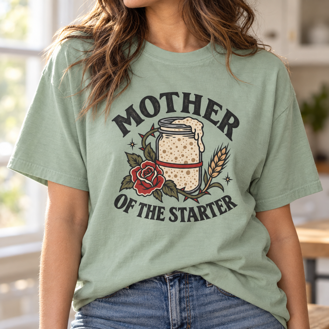 Woman modeling a bay vintage feel tee featuring a Mother of the Starter sourdough design with a starter jar, red rose, wheat, and bold vintage lettering.