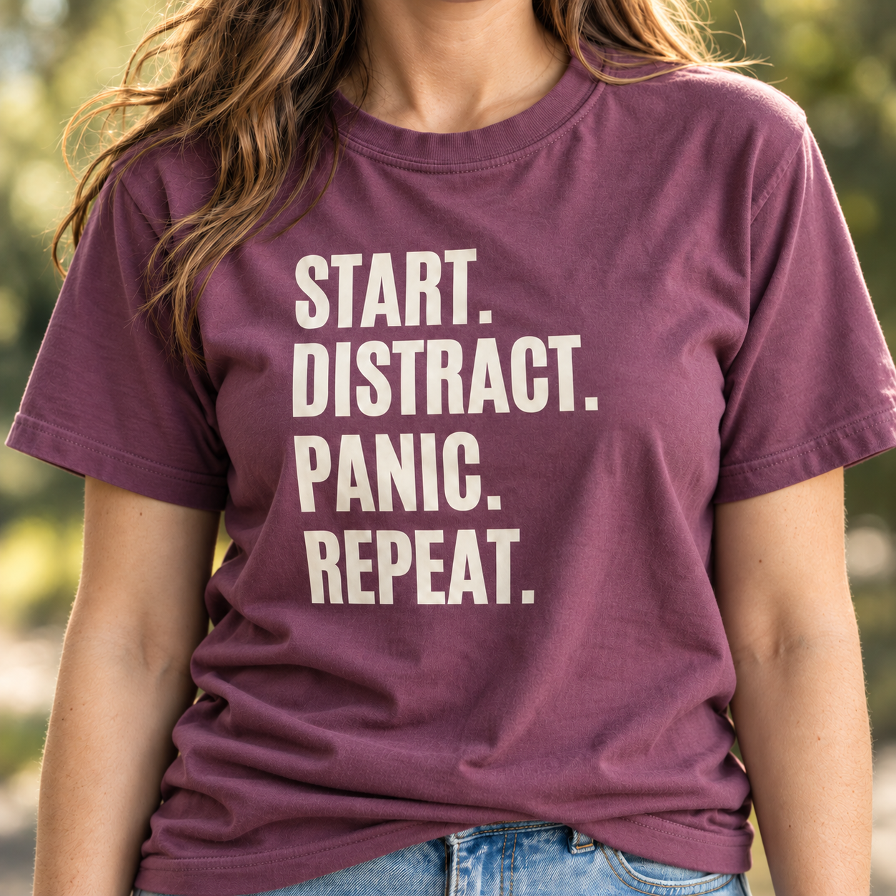 Woman modeling a berry vintage feel tee featuring a cream Start Distract Panic Repeat design in bold stacked lettering.
