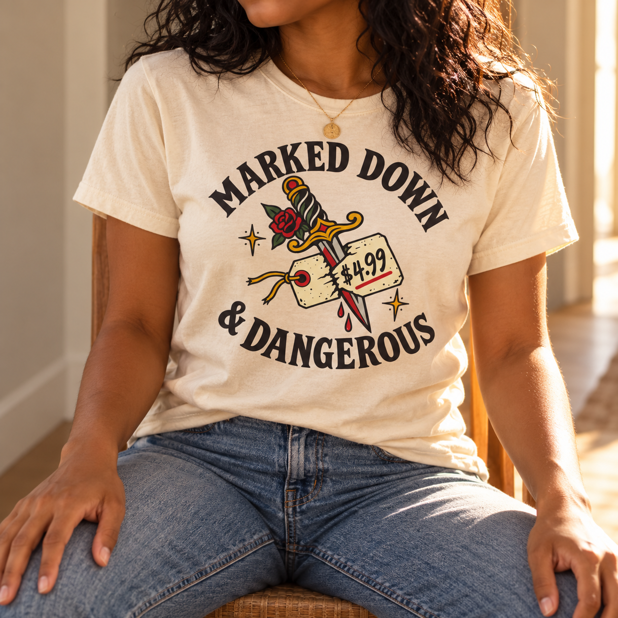 Model wearing the Marked Down & Dangerous Classic Fit Tee in Natural, with the front graphic visible in warm natural light.