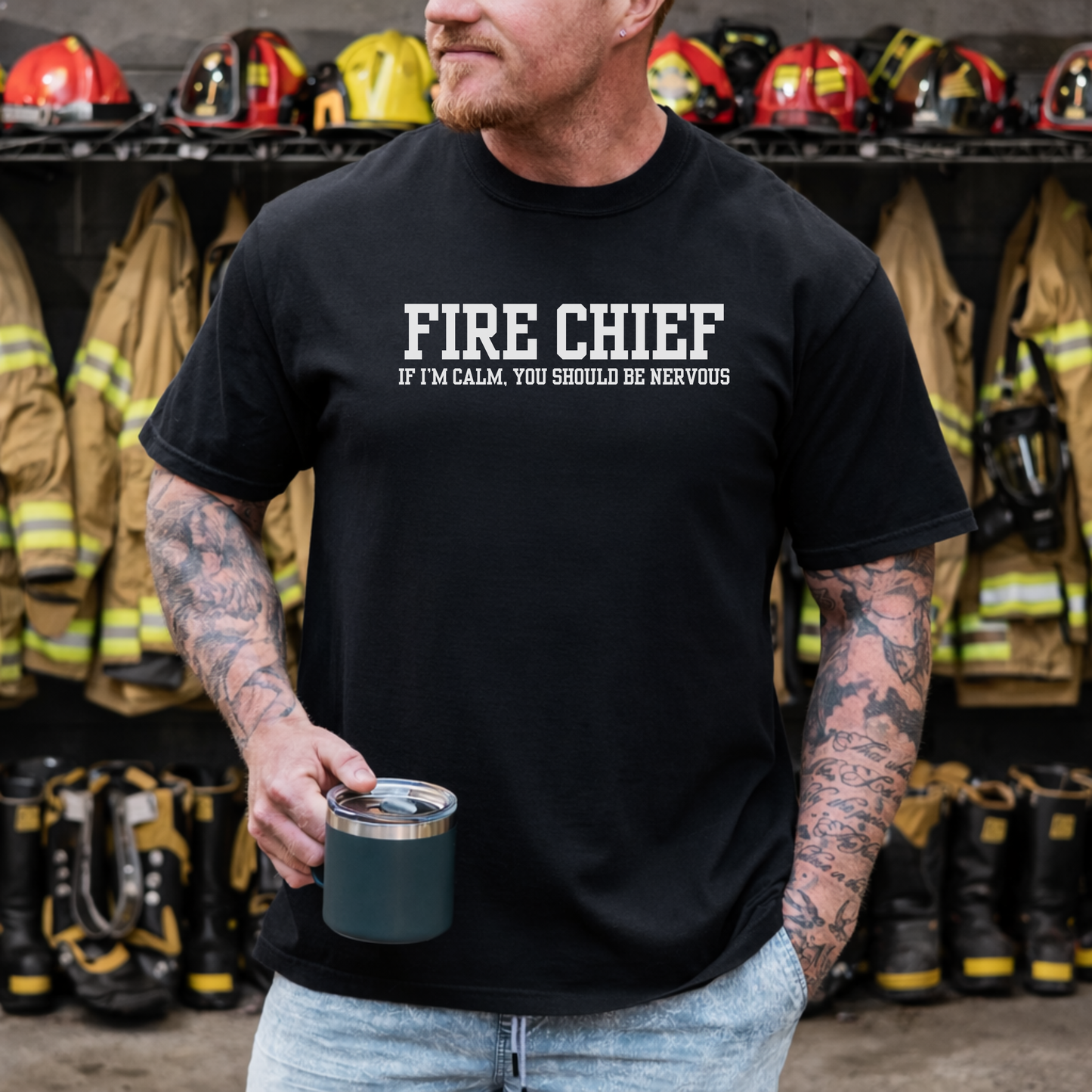 man wearing black t-shirt with “Fire Chief If I’m Calm You Should Be Nervous” text standing in firehouse locker room holding coffee