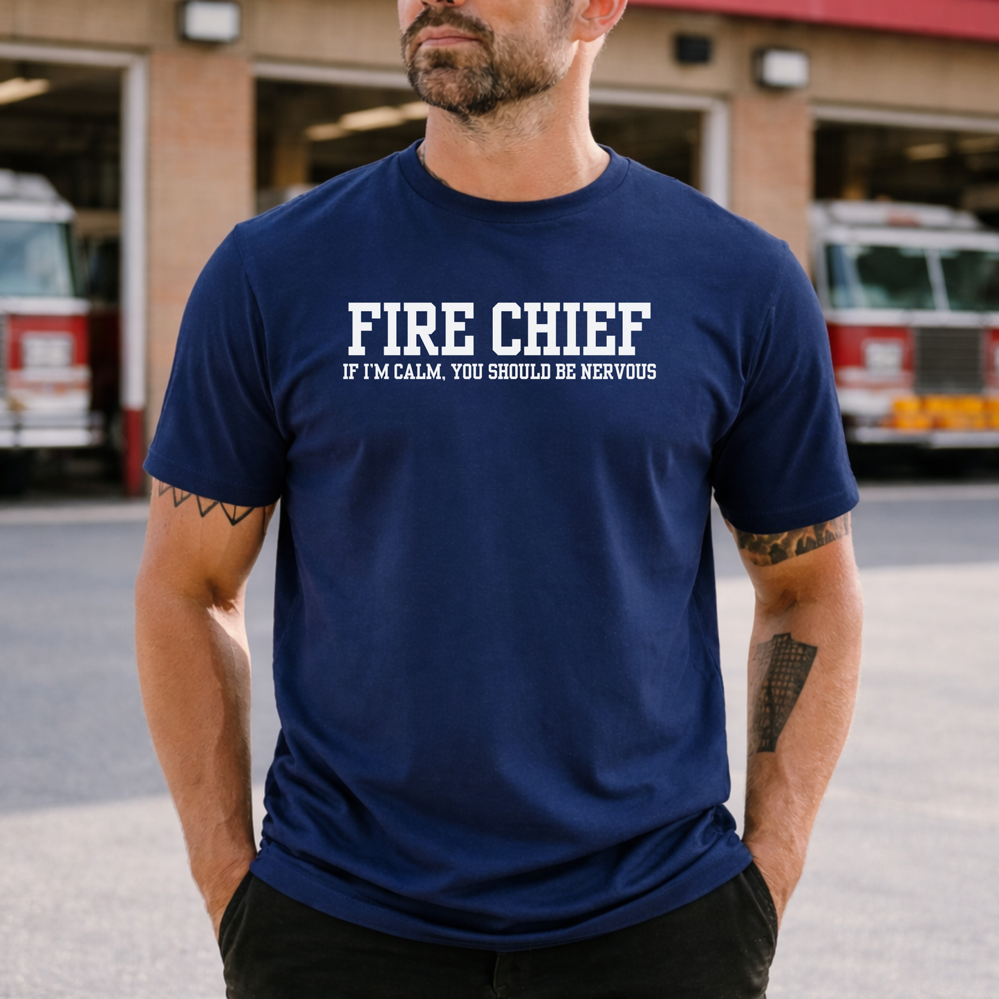 man wearing navy blue t-shirt with “Fire Chief If I’m Calm You Should Be Nervous” text standing in front of fire station