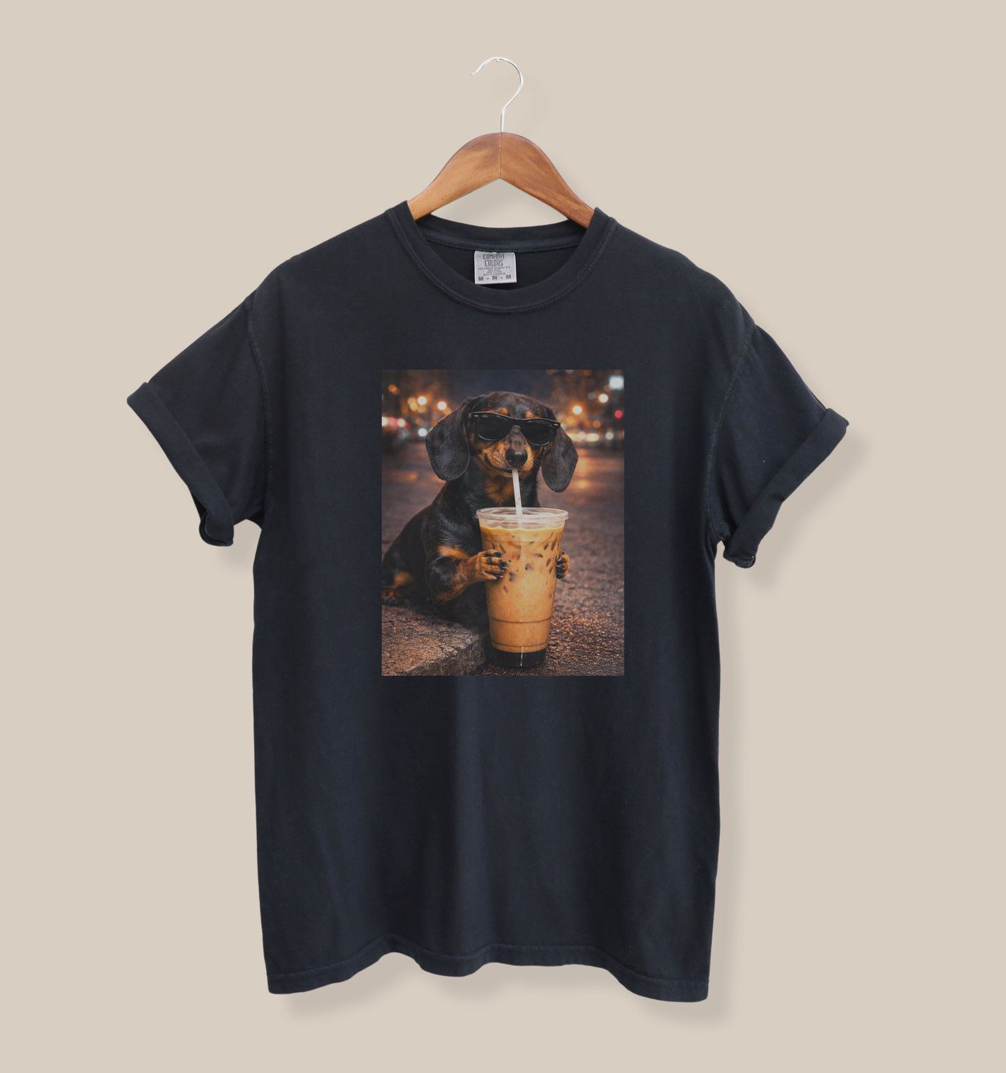black graphic t-shirt featuring a dachshund dog wearing sunglasses and drinking iced coffee on a city street at night