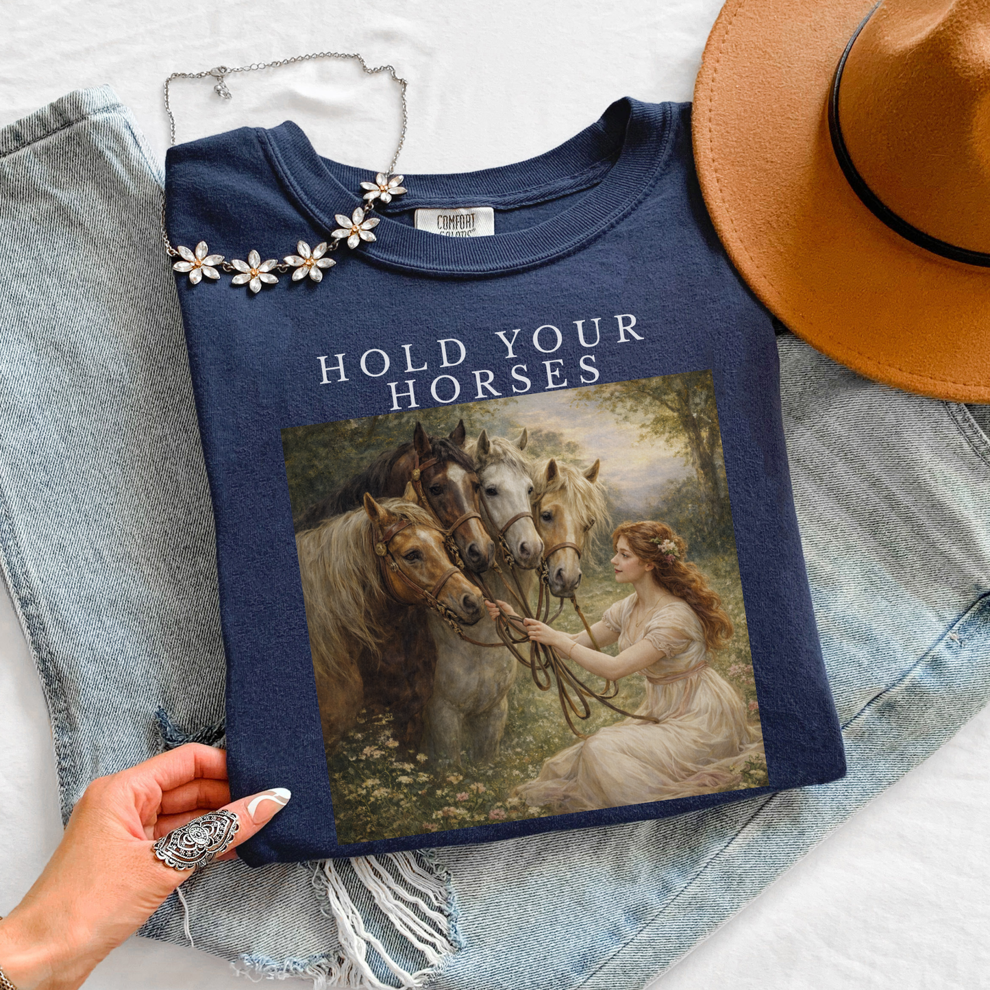 navy t-shirt with “Hold Your Horses” text and vintage horse illustration, styled flat lay with jeans, hat, and necklace