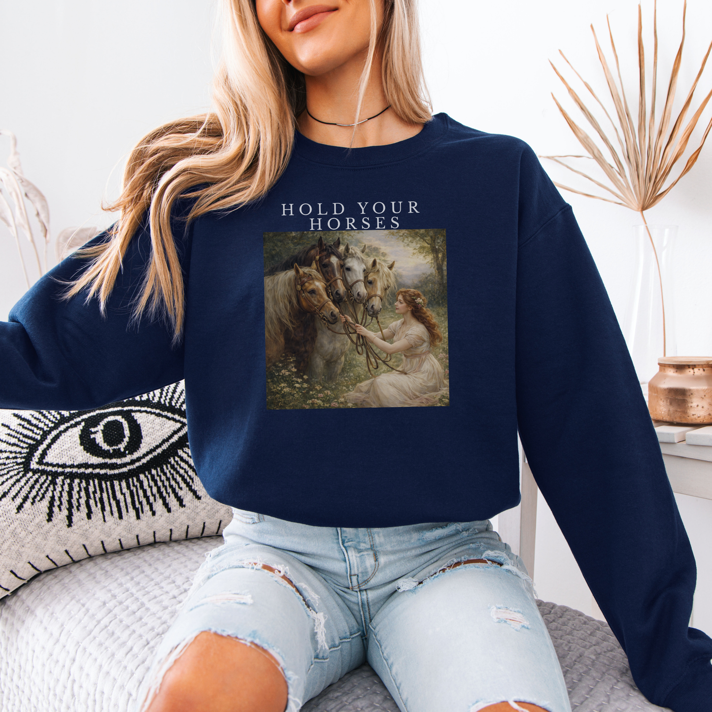 woman wearing navy “Hold Your Horses” graphic sweatshirt sitting indoors in cozy lifestyle setting